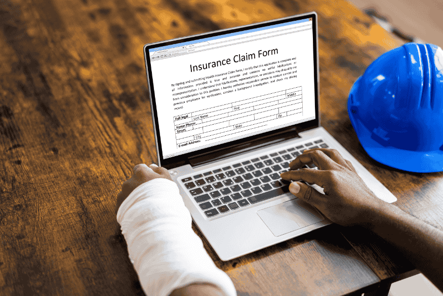 Verletzte Person mit eingegipstem Arm füllt online ein Versicherungsformular am Laptop aus.