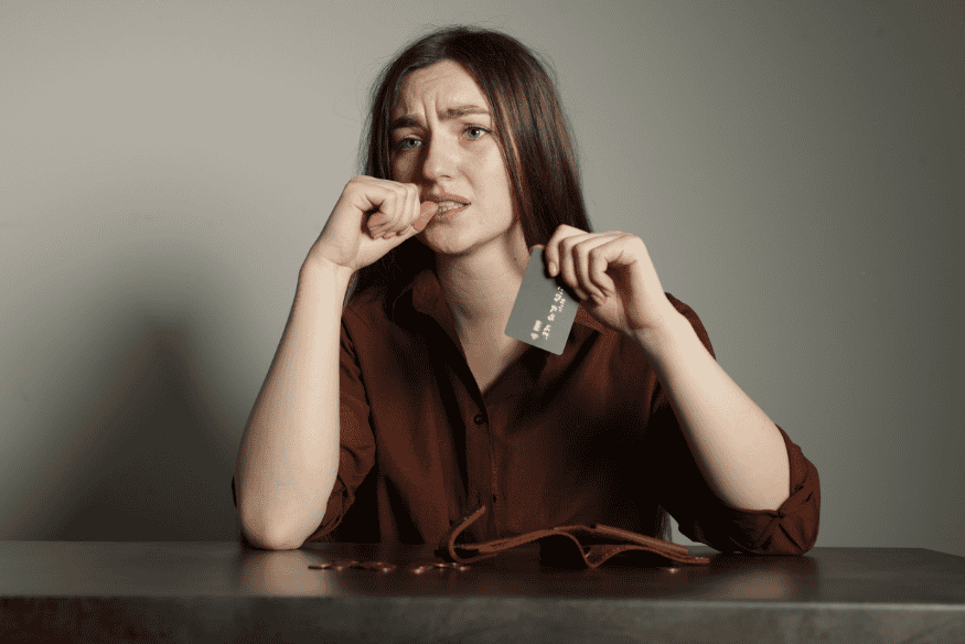 Besorgte Frau mit Kreditkarte in der Hand macht sich Gedanken über BNPL-Schulden und Ratenkäufe