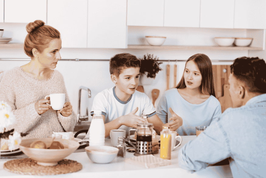 Familie sitzt am Küchentisch und spricht über Geld – gemeinsames Planen des Familienbudgets mit Kindern.