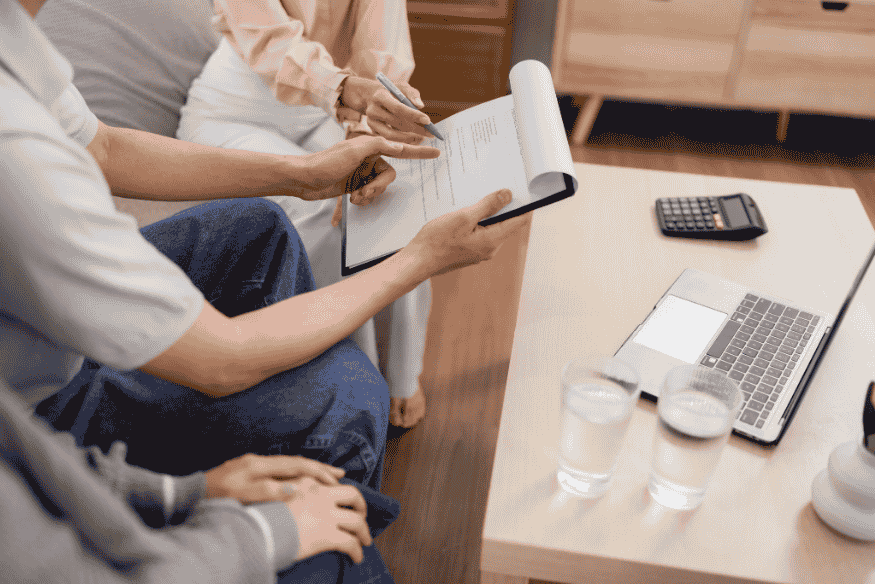 Familie sitzt mit Berater zusammen und prüft Vertragsunterlagen zur Krankenversicherung.