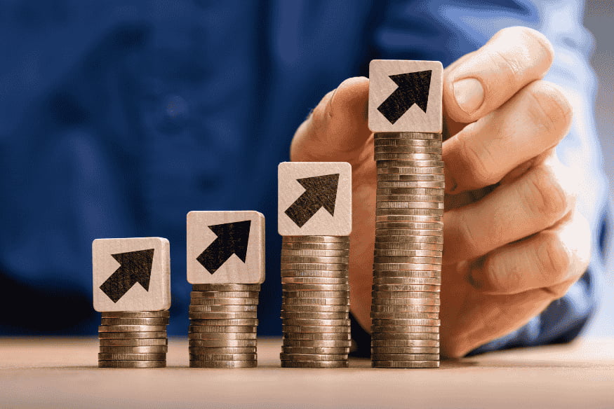 Münzstapel mit Pfeilen nach oben als Symbol für Inflation und steigende Lebenshaltungskosten im Alltag