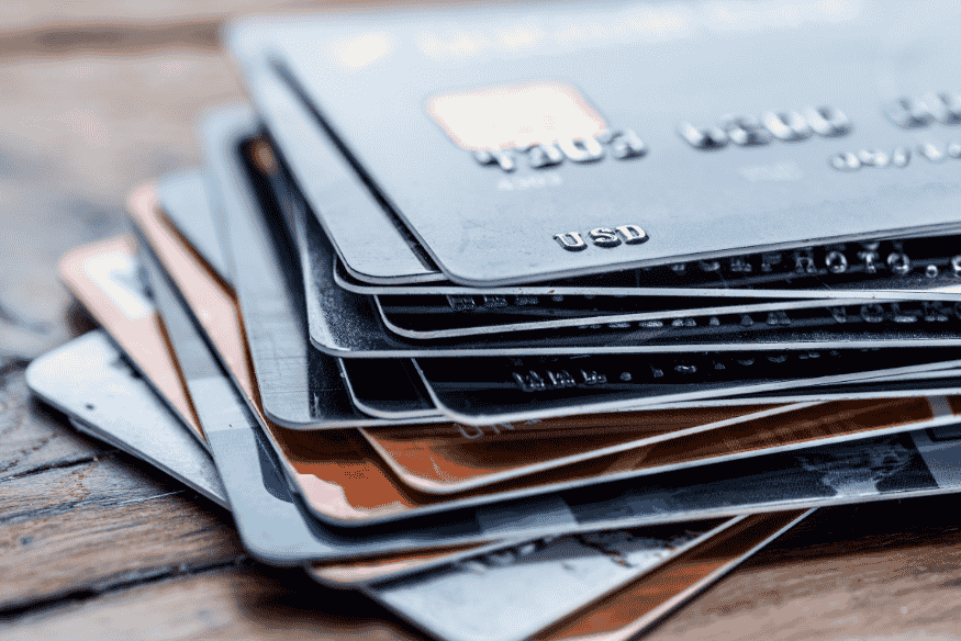 Stapel von Kreditkarten auf einem Holztisch – Darstellung verschiedener Anbieter und Konditionen.
