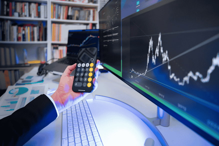 Anleger überprüft Kursverlauf auf großem Monitor und nutzt Taschenrechner zur Planung des Rebalancings