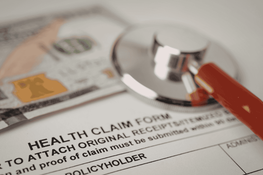 Stethoskop liegt auf einem Formular für Krankenversicherungsansprüche nach medizinischer Behandlung im Ausland.