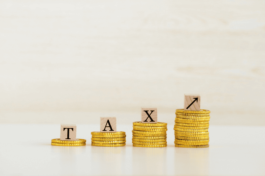 Wachsende Münzstapel mit Buchstaben TAX als Symbol für Steuern auf Kapitalerträge